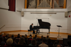 student plays piano on stage in front of an audience in the Moody Music Building